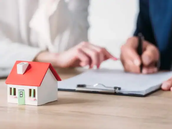 Housing agreement paperwork reviewed by real estate agent near model home